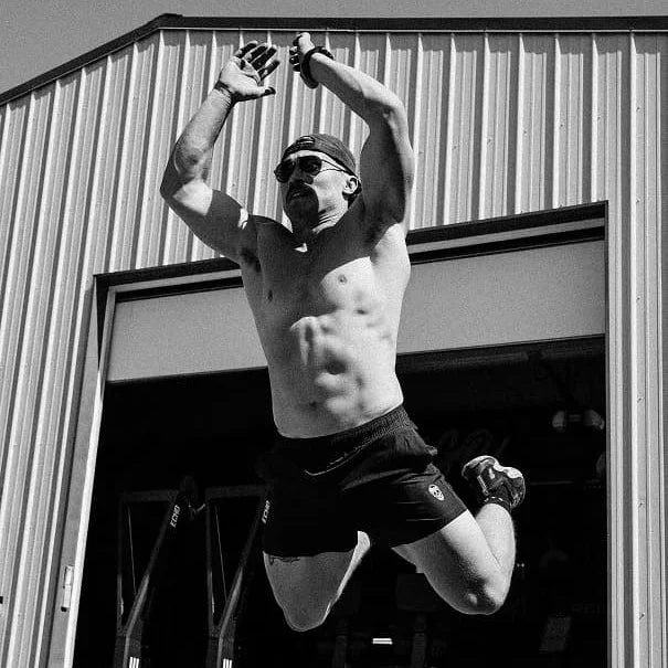 Athlete jumping in black and white in front of a warehouse door